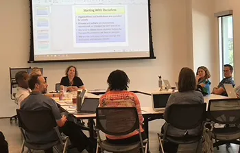 Photo of several people around a table at a Knapsack Institute small group.